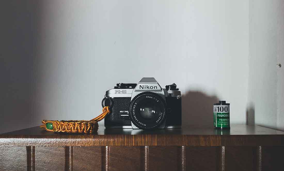 Vintage Nikon Film camera with a roll of film next to it.
