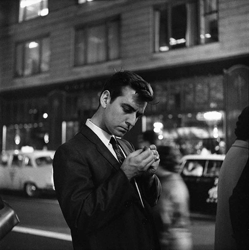 A man looking intently towards his hands portrait by Vivian Maier