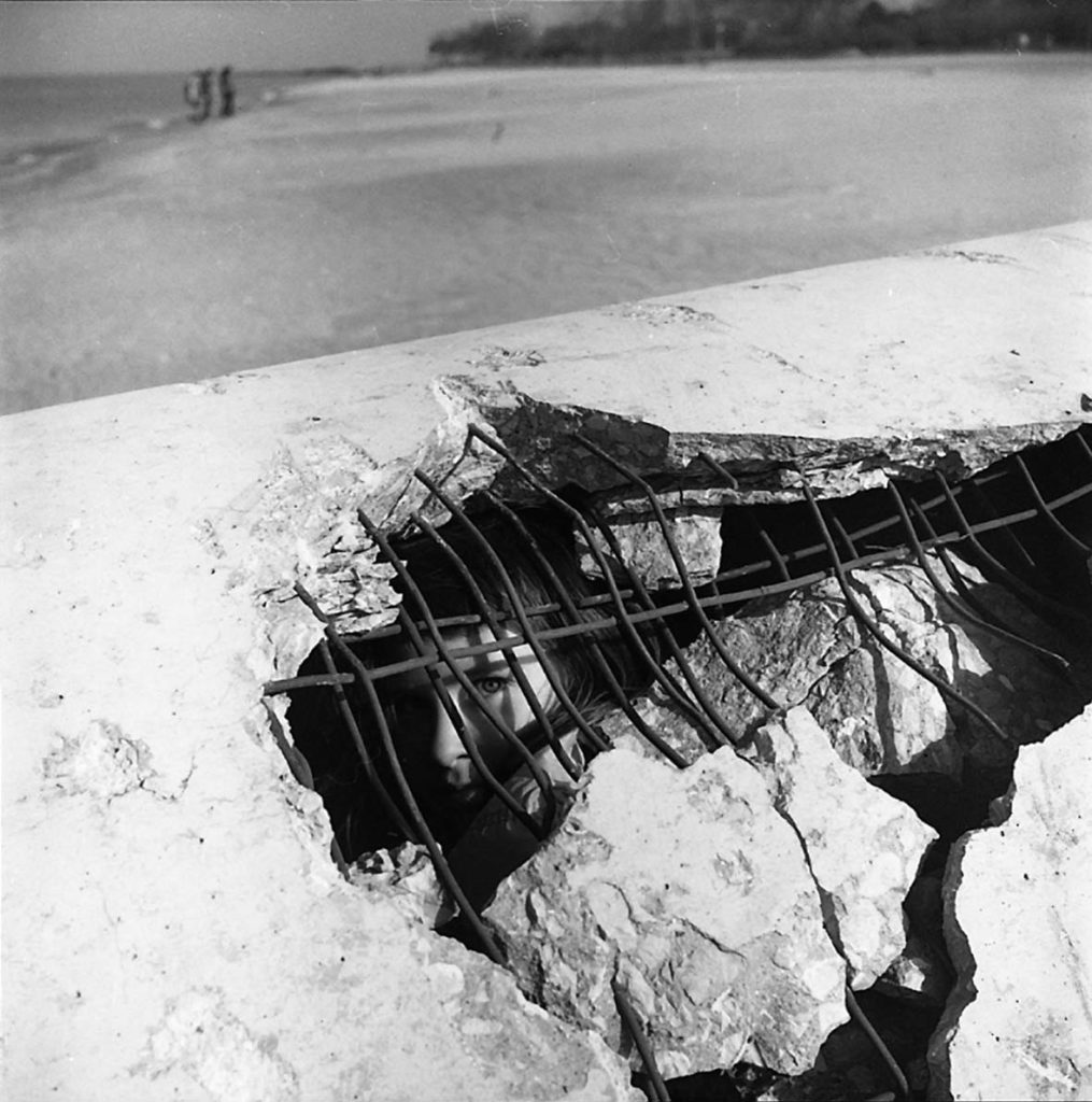 A young boy hiding under the rubble of a broken road