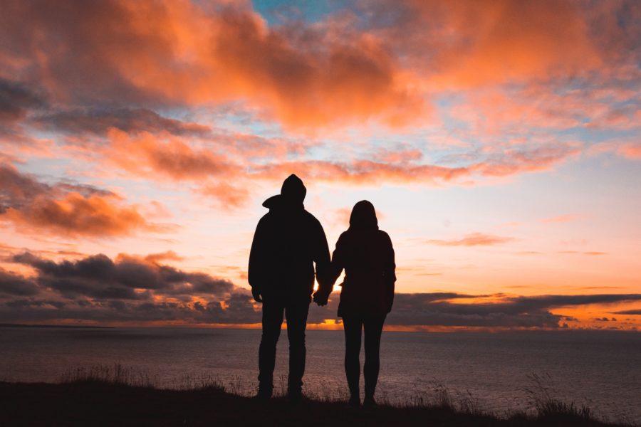 man and a woman holding hands near a waterbody at dusk