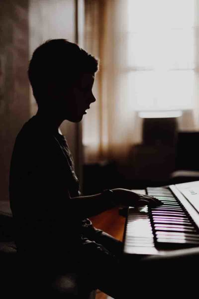 A young boy playing piano in a dark room