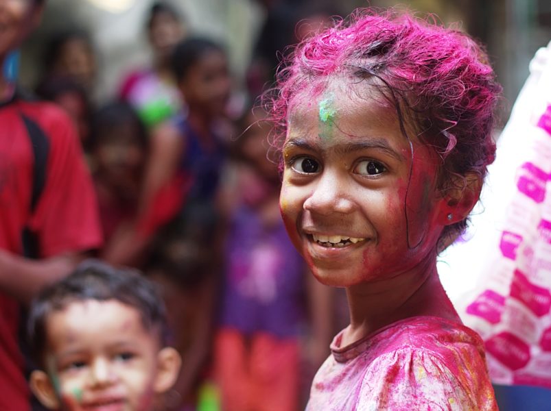young girl looking at the camera covered in colors