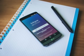 An android cell phone on a blue notebook with Instagram login page opened on it