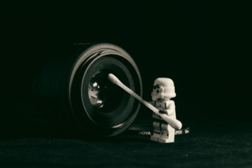 A white storm trooper cleaning a camera with an earbud